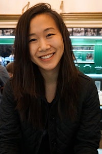 a young asian woman smiling at a table in a restaurant